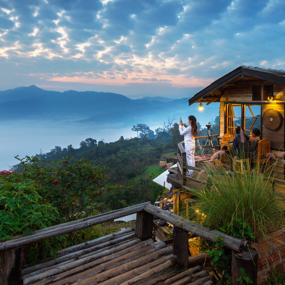 Woman taking a photo to morning mist at Phu Lang Ka, Phayao in T